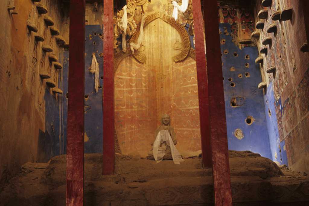 Tibet Guge 06 Tsaparang White Temple 09 12 Jowo Khang Chapel Along the centre of the rear wall is the smaller inner chamber called Jowo Khang, which is open to the assembly hall and provides the only light to the entire temple. The chapel once had a gigantic gilt-bronze statue of Shakyamuni on a massive stand. The caretaker has replaced the figure of Shakyamuni with one of his own statues. The left and right walls have four rows of tiny, sculpted divinities, each supported on its own pedestal. Some of the gilded clay images in the higher series are still intact. Photo � <a class=